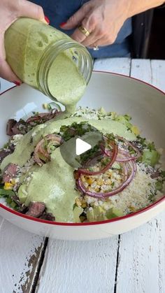 a person pouring dressing into a bowl filled with food