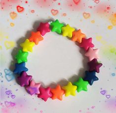 a rainbow bracelet with stars on it and hearts in the background, sitting on a table