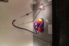 a purple and red toy car hanging on the wall next to a black tile floor