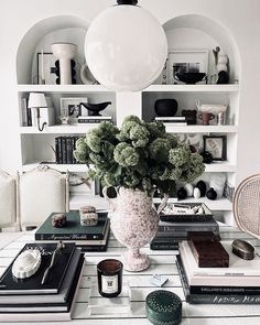 a table topped with books and a vase filled with flowers next to other books on shelves