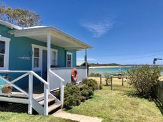 a small blue house sitting on top of a lush green field next to the ocean