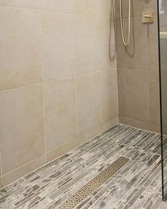 a walk in shower sitting next to a tiled wall and floor with a glass door