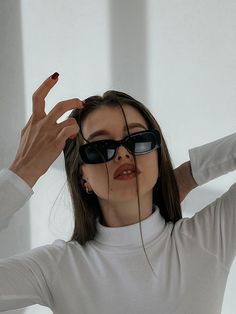 a woman wearing sunglasses and holding her hands behind her head