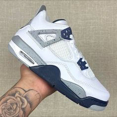 the air jordan 4 is being held up by someone's hand with a rose tattoo on