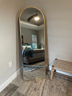 a large mirror in the corner of a living room next to a footstool