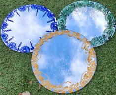 three plates sitting on top of a green grass covered field with blue and yellow designs