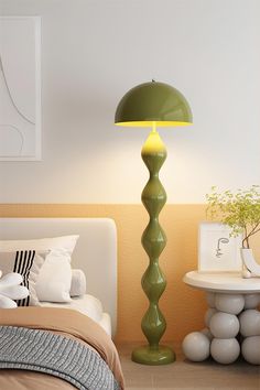 a green lamp sitting on top of a bed next to a white table and chair