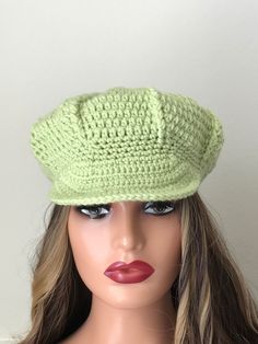 a mannequin head wearing a green crocheted hat on top of a wig