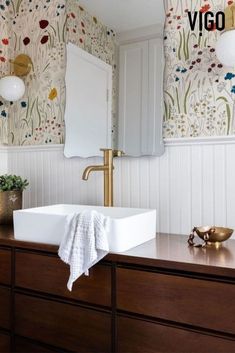 a white sink sitting on top of a wooden dresser next to a wall mounted mirror