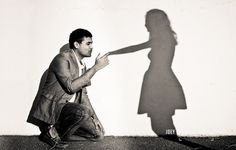 a man kneeling down in front of a shadow of a woman holding her hand out