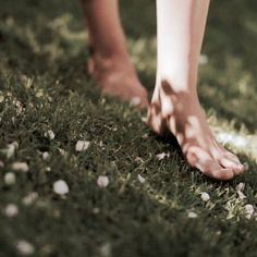 a person standing in the grass with their bare feet