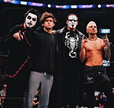 three men with face paint standing next to each other in front of an audience at a wrestling match