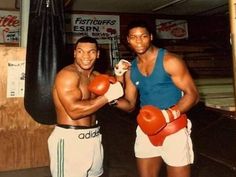 two men standing next to each other holding boxing gloves