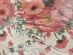 an old quilt with pink and green florals on it's edges, as well as red flowers