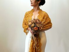 a woman wearing a yellow shawl holding a bouquet of flowers