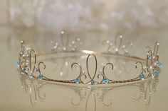 a tiara with pearls and blue stones on the bottom is shown in close up