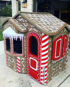 a house made out of cardboard and decorated like a gingerbread house with icing on the roof