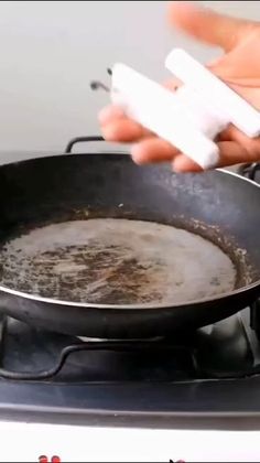 a frying pan filled with food on top of a stove next to a person's hand