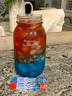 a mason jar filled with blue liquid next to two candy bar wrappers on a counter