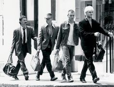 black and white photograph of three men walking down the street with bags in their hands