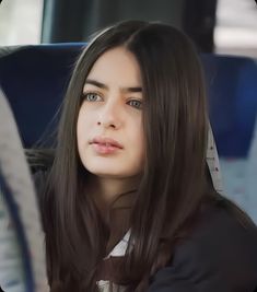 a woman with long brown hair sitting on a bus