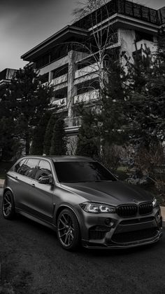 a black and white photo of a bmw suv parked in front of a large building