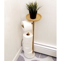 there is a toilet paper holder in the corner with a plant on it and a roll of toilet paper next to it