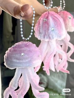 two pink and white jellyfish necklaces being held by someone