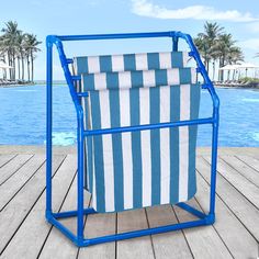 a blue and white striped towel rack sitting on top of a wooden deck next to a pool