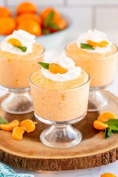 three small desserts with whipped cream and orange zest on a wooden platter