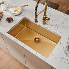 a kitchen counter with a gold sink and some ingredients on the counter top next to it