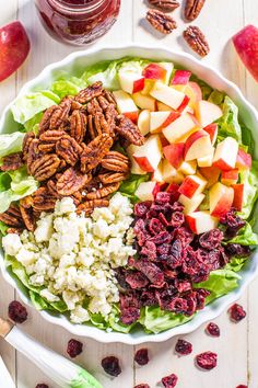 a salad with apples, cranberries and pecans in it on a table