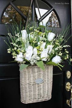 a basket with flowers hanging from the front door