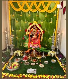 an idol is set up in front of a green backdrop with yellow flowers and candles