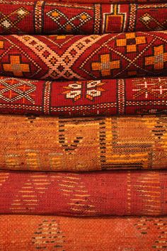 a pile of colorful rugs stacked on top of each other