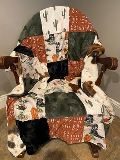 a chair covered in a blanket with cats and cactuses on it, sitting next to a wall