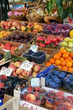 various fruits and vegetables are on display at a farmers'market, including plums, peaches, apples, blueberries