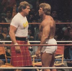 two men standing next to each other in a wrestling ring