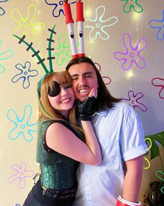 two people standing next to each other in front of a wall with decorations on it