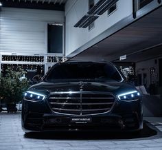 the front end of a black mercedes s - class parked in a parking lot at night