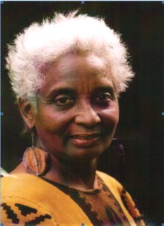 an older woman with white hair and earrings on her head, smiling at the camera