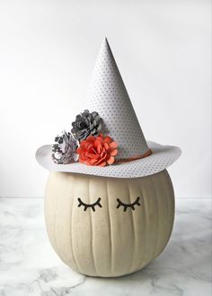 a pumpkin with a white hat on it's head and flowers in the eyes