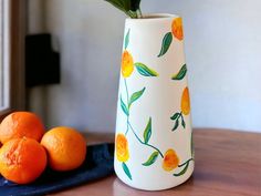 there is a vase with oranges on the table