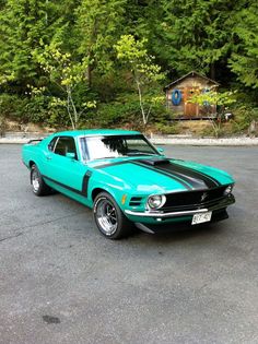 a turquoise mustang with black stripes parked in a parking lot