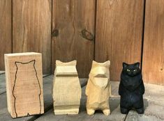 three wooden cat figurines sitting on top of a wooden table next to each other