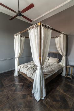 a four poster bed with white drapes on the top and bottom, in a bedroom