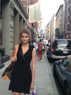 a woman is walking down the street with her hand in her pocket and shopping bags