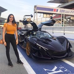 a woman standing next to a black sports car