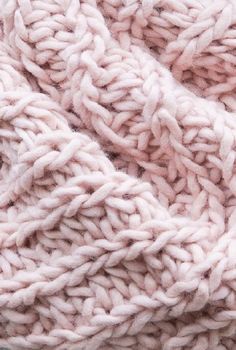 the texture of a knitted blanket is shown in pink and white colors, close up