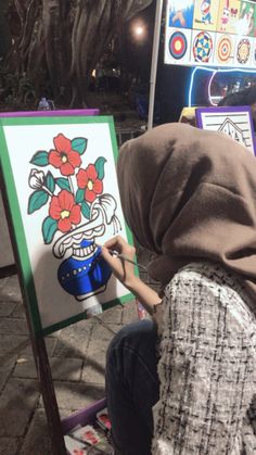 a person sitting in front of an easel with a painting on it's side